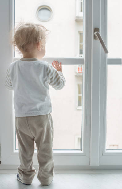 istock Cute boy at home looking through the window 1222287223