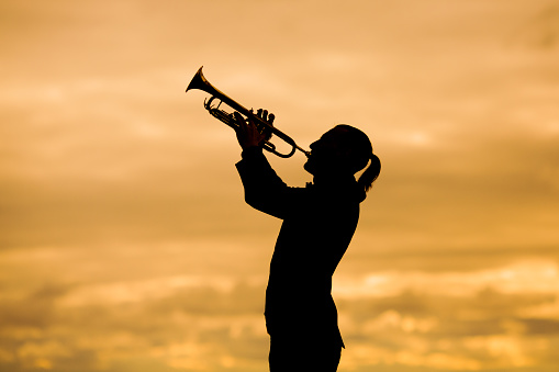 silhouette of man playing trumpet against yellow background