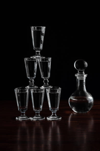 decantador de cristal ou jarra de vodca e copos pirâmide torre sobre mesa de madeira em restaurante, fundo preto - decanter crystal carafe glass - fotografias e filmes do acervo