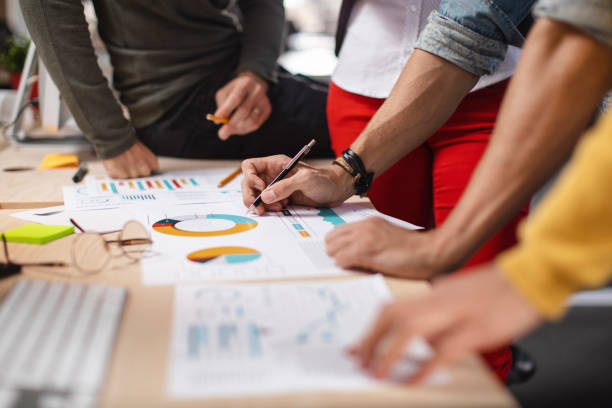 Pie charts experts Close-up shot of a group of colleagues going through paperwork together in the office travel agency stock pictures, royalty-free photos & images