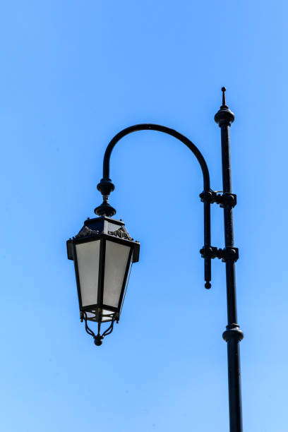 istock Old lantern on a metal post against blue sky 1222295644