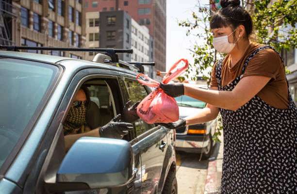 istock Smiling Masked Restaurant Worker During Covid-19 Lockdown Handing Order Through Car Window 1222296699