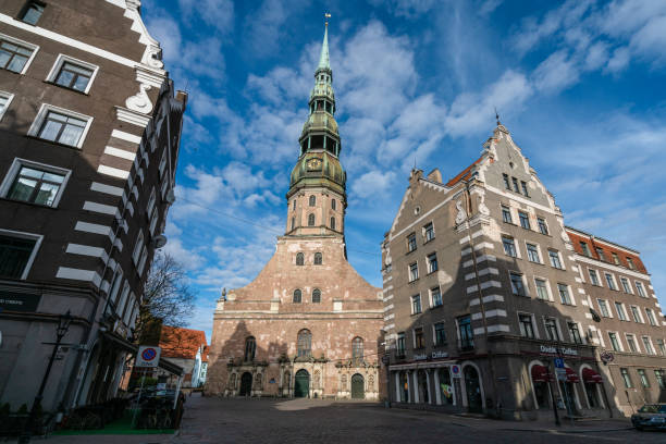 Riga, Latvia – April 26, 2020: St. Peters Church in springtime. Blue sky with white clouds can be seen in the sky. St. Peter's was a Catholic church until 1523, when it turned Lutheran. Its wooden tower, the highest in Europe at that time, was destroyed several times. It first collapsed in 1666 and was rebuilt a year later