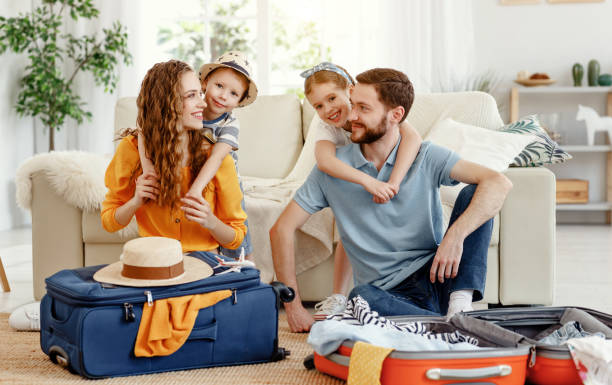 Cheerful family with suitcases on floor looking at camera