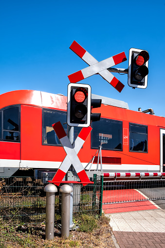 Road signs at the railway crossing with traffic light and barrier. Railroad warning with flashing red light