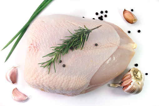 fresh raw chicken breast, double, whole, with herbs, pepper, garlic, isolated on white background. Top view