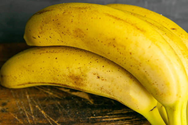 istock Three bananas lie on old wooden boards. Close-up 1222303354