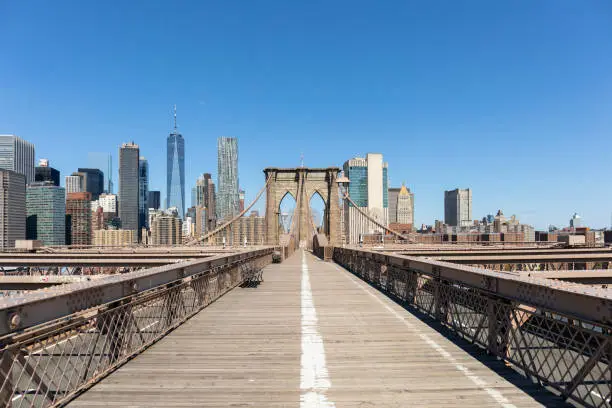 View of lower Manhattan and the freedom tower from an empty Brooklyn bridge pedestrian walkway.