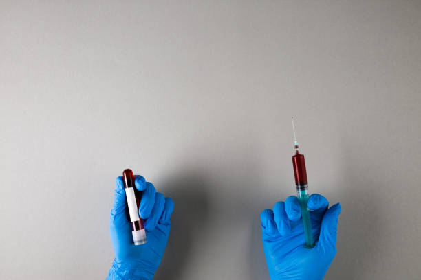 istock Hands in rubber gloves holding syringe and test tube with sample 1222310400
