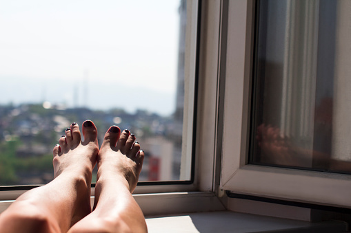 young woman getting tan on a window sill