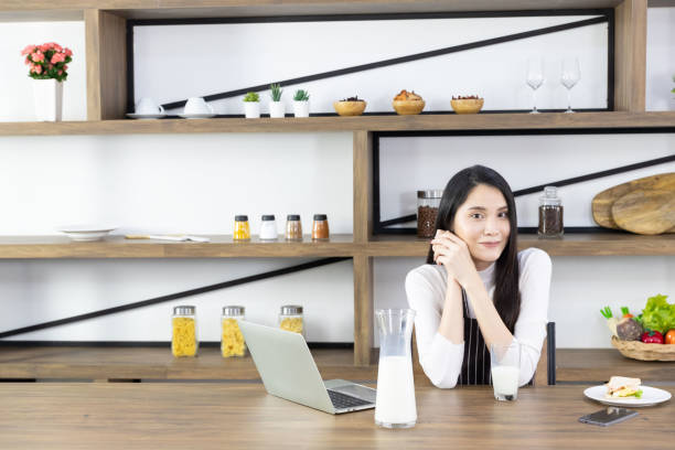 istock Asian woman holding hand under chin in kitchen. 1222323687