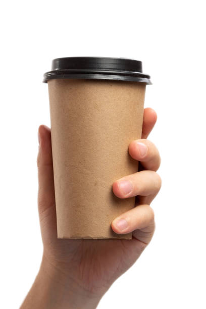 istock Breakfast and coffee theme: man's hand holding empty paper coffee cup with a brown plastic cap isolated on a white background in the studio, advertising coffee 1222323731