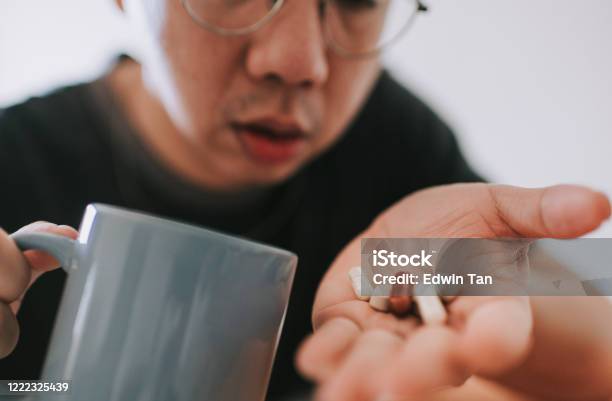 Seorang Pria Dewasa Tengah Asia Cina Dengan Gejala Penyakit Flu Mengambil Obat Yang Berfokus Pada Pil Obat Palem Tangan Foto Stok - Unduh Gambar Sekarang