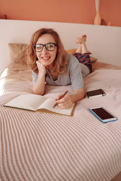 istock Young woman taking notes in bed and smiling 1222326457