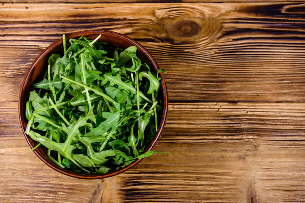 istock Ceramic bowl with arugula leaves on wooden table. Top view 1222328951