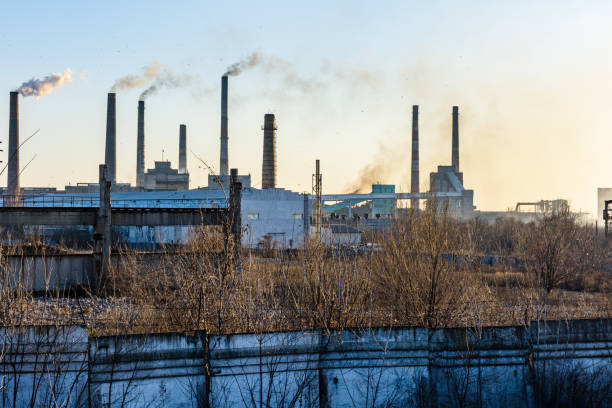 vue sur les tuyaux de fumée de l’usine au coucher du soleil - global warming smog city pollution photos et images de collection