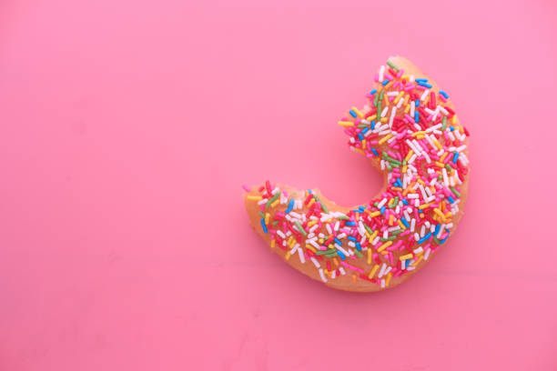 Half eaten donut on pink background