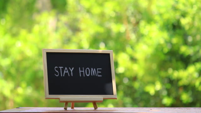 STAY HOME lettering on black chalkboard. Covid-19 coronavirus concept background.