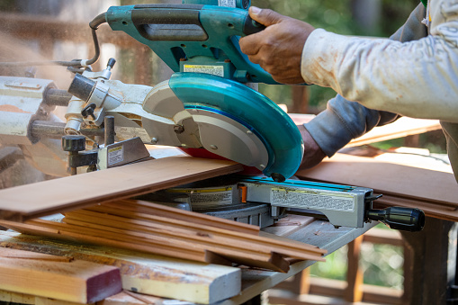 Man cutting wood with radial arm saw.