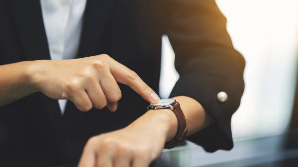 деловая женщина, указывающая на наручные часы на свое рабочее время в ожидании кого-то - checking the time women impatient wristwatch стоковые фото и изображения