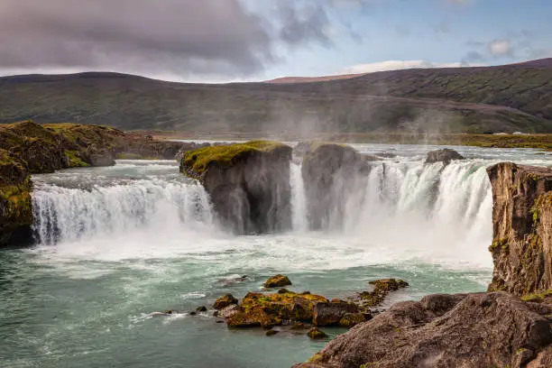 Majestic Godafoss - Goðafoss - Waterfall of the Gods - Waterfall under moody skyscape in late summer, located in the North of Iceland. The water of the river Skjálfandafljót falls from a height of 12m over a width of 30m. Godafoss Waterfall, Fossholl, Sprengisandur, Northern Iceland, Iceland, Nordic Countries, Europe.