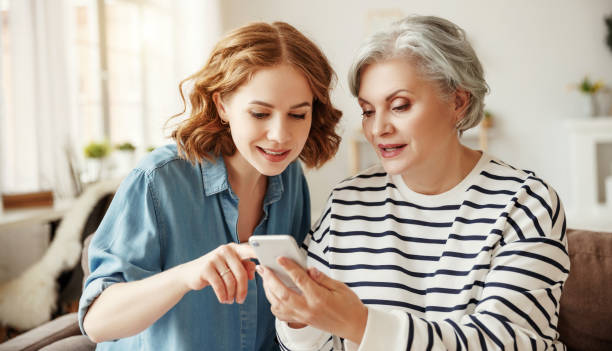 istock Cheerful mother and daughter using smartphone on sofa 1222339859