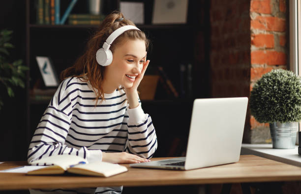 istock Excited woman in headphones having conversation on video chat while using laptop at home 1222340647