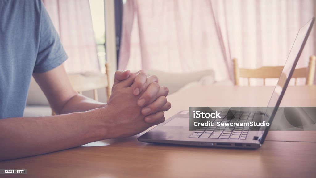 Praying hands with laptop,  worship online at home, streaming online church service, social distancing concept Praying Stock Photo