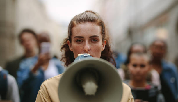 activista femenina protestando con megáfono durante una huelga - protest fotografías e imágenes de stock