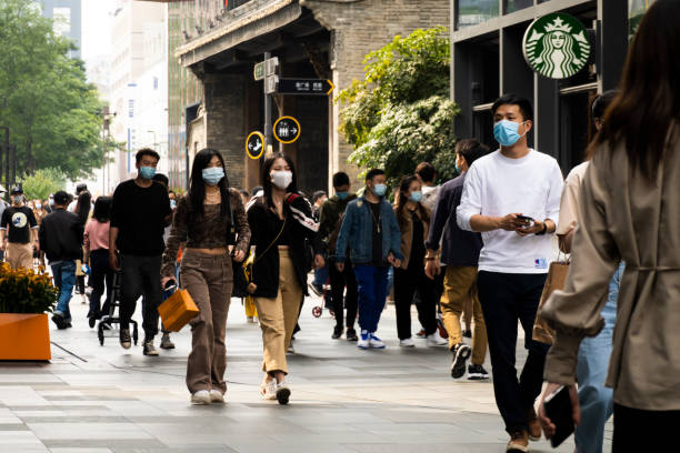 junge leute gehen mit gesichtsmaske in der innenstadt - store market china city street stock-fotos und bilder