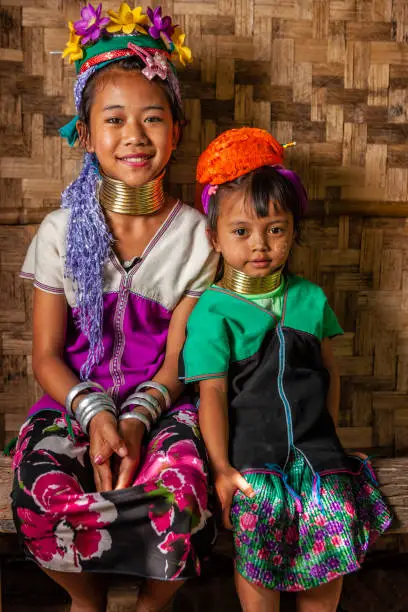 A long-neck little girls from Padaung (Karen) tribe resting in the village, Mae Hong Son Province in Northern Thailand.