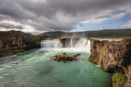 Majestic Godafoss - Goðafoss - Waterfall of the Gods - Waterfall under dramatic, moody skyscape in late summer. The water of the river Skjálfandafljót falls from a height of 12m over a width of 30m. Godafoss Waterfall, Fossholl, Sprengisandur, Northern Iceland, Iceland, Nordic Countries, Europe.