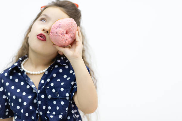 Little girl hiding behind a pink donut.