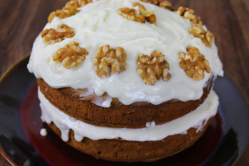 Stock photo showing a home made carrot cake topped with cream cheese flavoured butter cream and decorated with walnut halves.