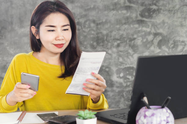 happy Asian woman paying for electricity bill by smart phone happy Asian woman paying for electricity bill by smart phone energy bill photos stock pictures, royalty-free photos & images