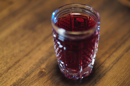 Tincture of red color in a crystal glass stands on a wooden table