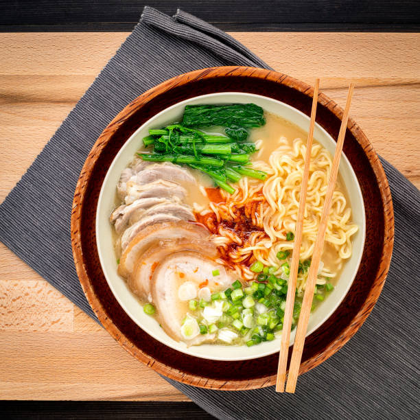 Asian ramen noodle pork bone based soup with pork chashu on cutting board background.