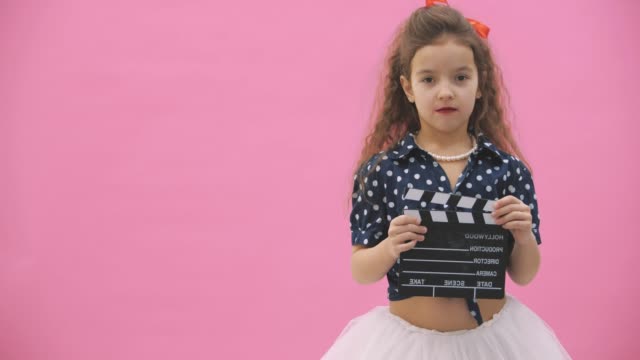 4k slowmotion video where curly girl holding a clapboard in hands.