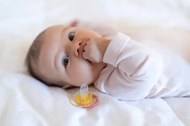 The close-up of baby girl in bed sucking fist