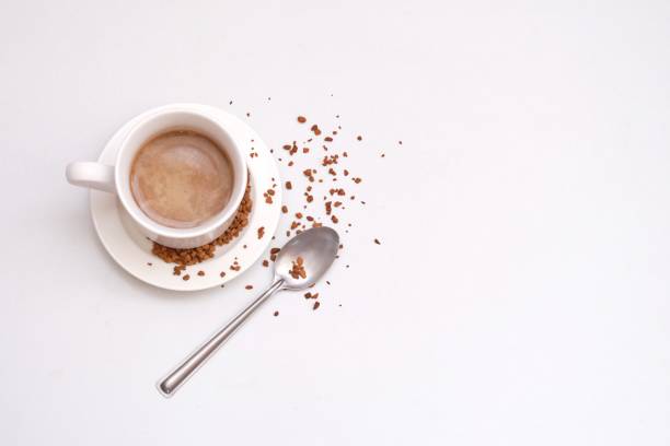 istock Blurred a cup of hot coffee  with a silver tea spoon top view on white isolated background with copy space 1222372830