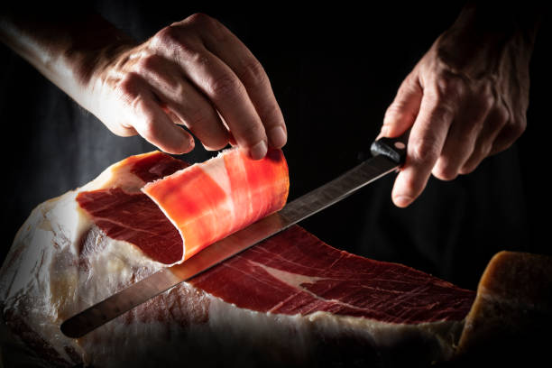 istock Iberian ham serrano ham slice cutting hands and knife 1222373090