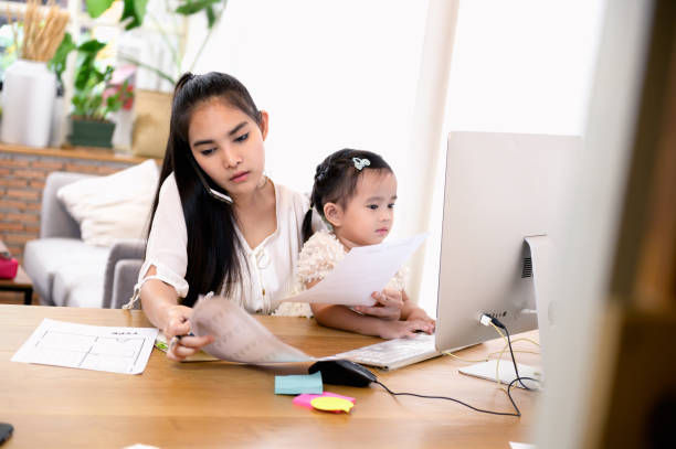 piękna azjatka w średnim wieku lub bizneswoman pracująca na swoim telefonie komórkowym i laptopie w domu i dbać o swoją córeczkę. - working mother child emotional stress mother zdjęcia i obrazy z banku zdjęć