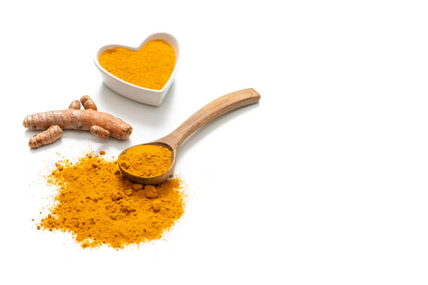 Turmeric curcuma in heart shape bowl and wooden spoon isolated on white