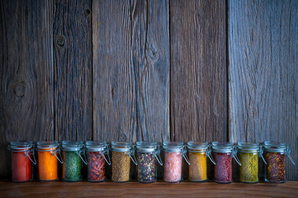 Spices herbs condiments seasoning pots in a row on rustic wooden table background leaving copy space