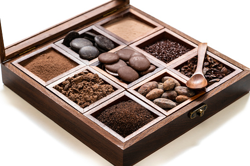 Chocolate assorted wood box with coca beans chocolate drops cacao powder in a row on white background