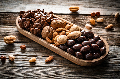 Chocolate nuts almonds and peanuts on vintage rustic board wood table