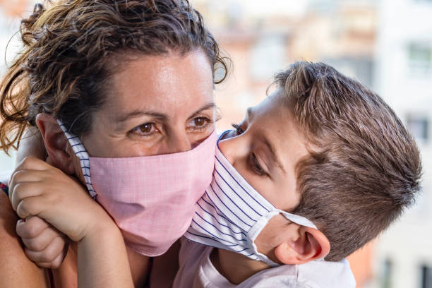 mały chłopiec całuje swoją mamę maskami ochronnymi - kissing child family isolated zdjęcia i obrazy z banku zdjęć