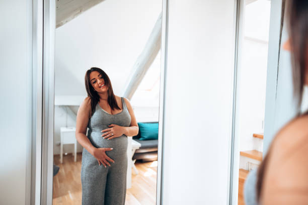 istock Pregnant woman looking her self at the mirror 1222378723