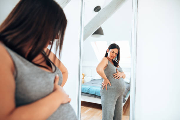istock Pregnant woman looking her self at the mirror 1222378852