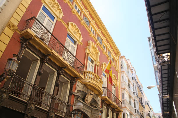 Looking up at the beutiful buildings & architecture lining La Calle Mayor, which is the heart of Cartagena. The street connects Plaza de España with the port. All along, little shops, bars and restaurants., Cartagena, Murcia, Spain.